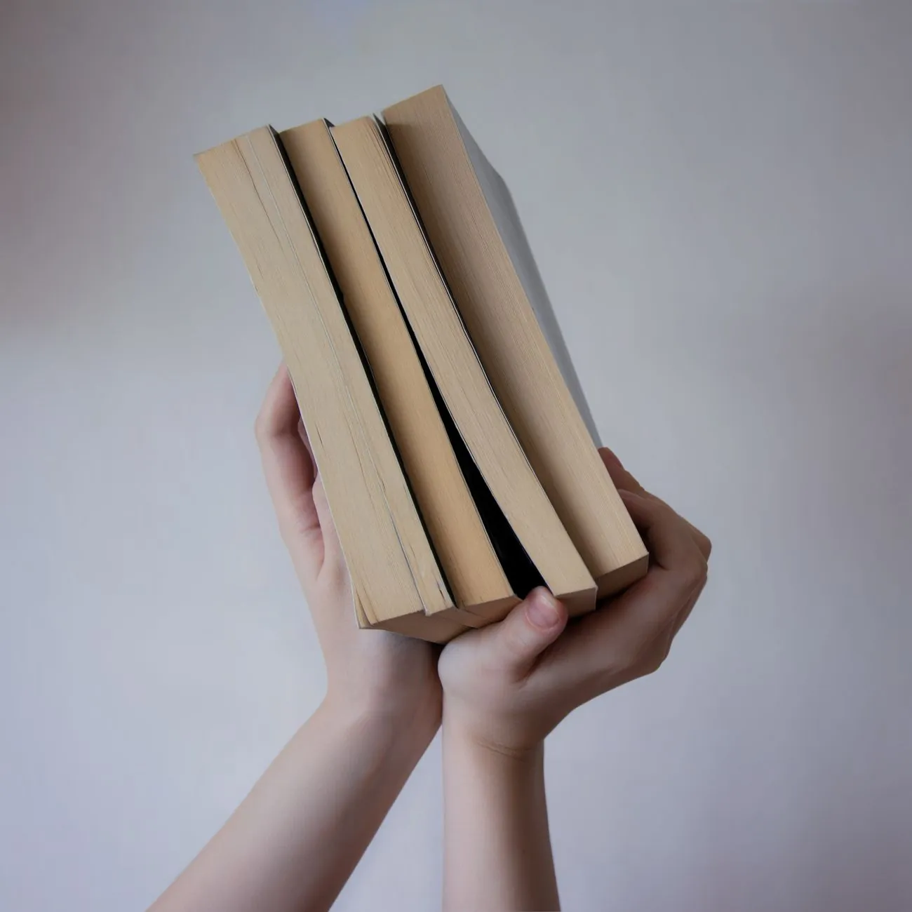 Hands holding a stack of books, standing in for studio financial documents